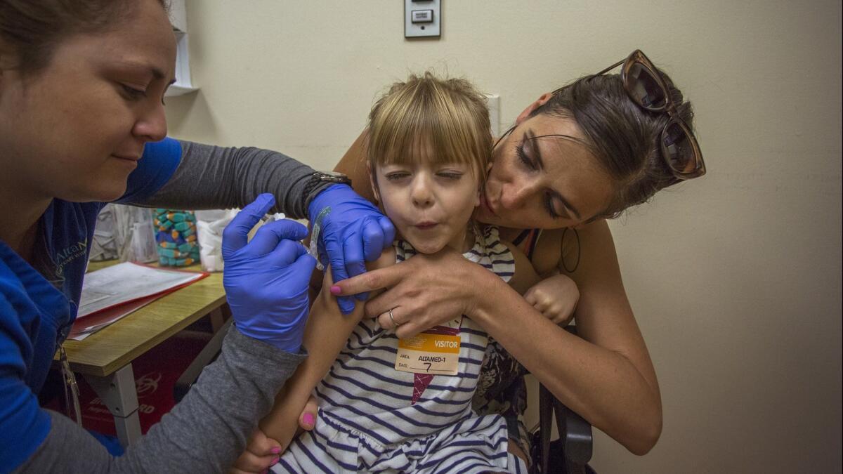 A child, 4, holds her breath in the arms of her mother as she receives a vaccination at Children's Hospital Los Angeles.