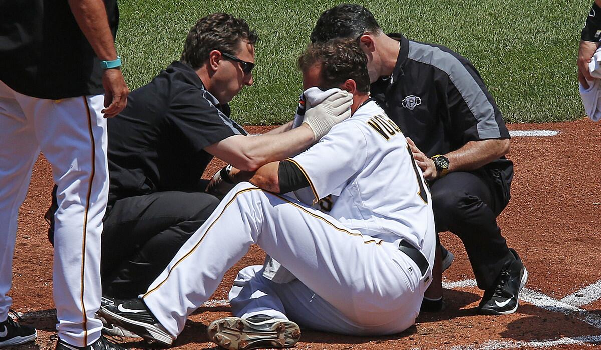 Pittsburgh Pirates pitcher Ryan Vogelsong, center, is helped by team trainers after being hit in the head by a pitch from Colorado Rockies pitcher Jordan Lyles in the second inning on Monday.