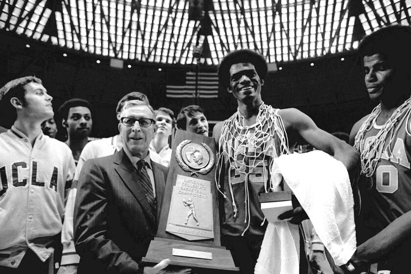 UCLA coach John Wooden holds the NCAA championship trophy. Sidney Wicks  wears part of the net around his neck. 