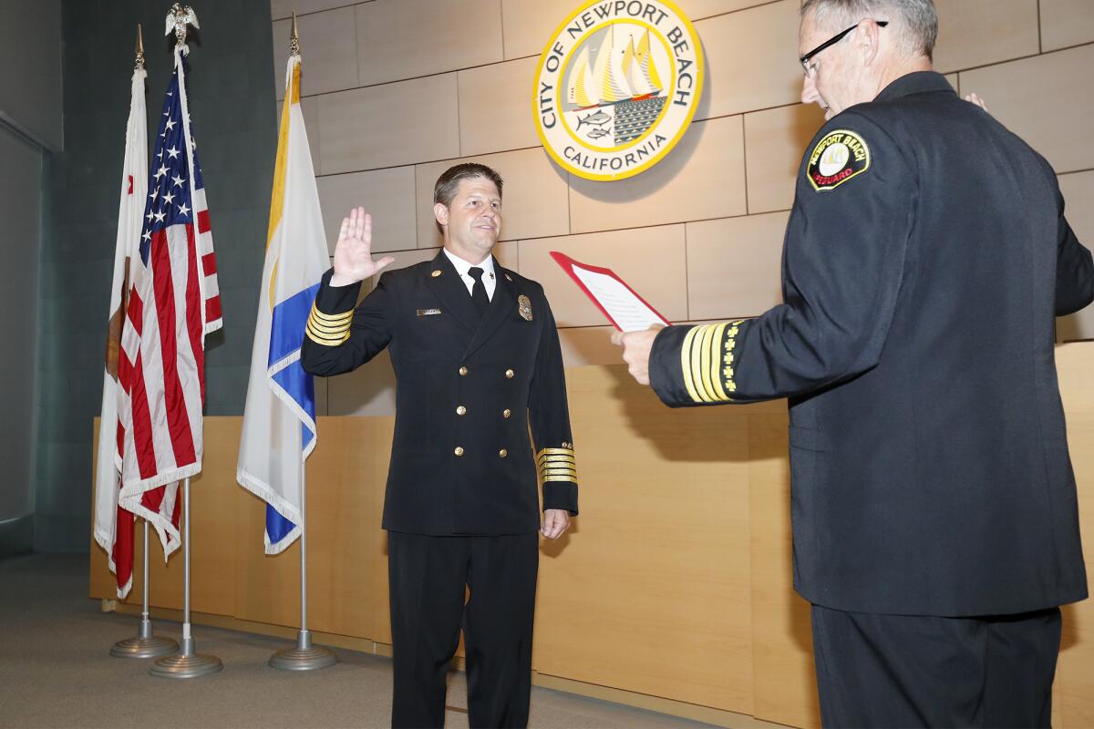 Newport Beach's new fire chief, Jeff Boyles, left, repeats the oath of office as he is sworn in by lifeguard Battalion Chief Mike Halphide during a badge-pinning ceremony Wednesday at City Hall.