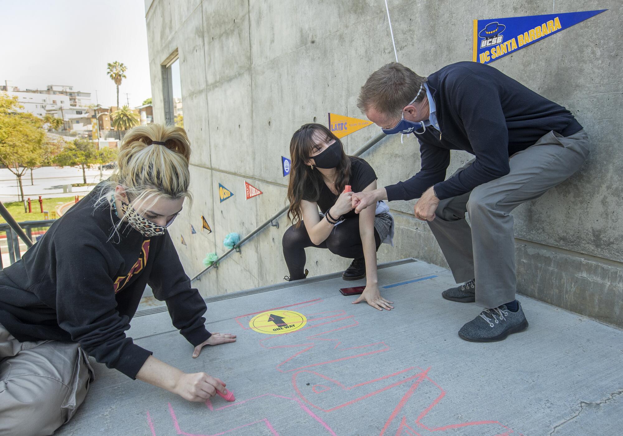 People write in chalk on the ground as Austin Beutner gives a fist bump.