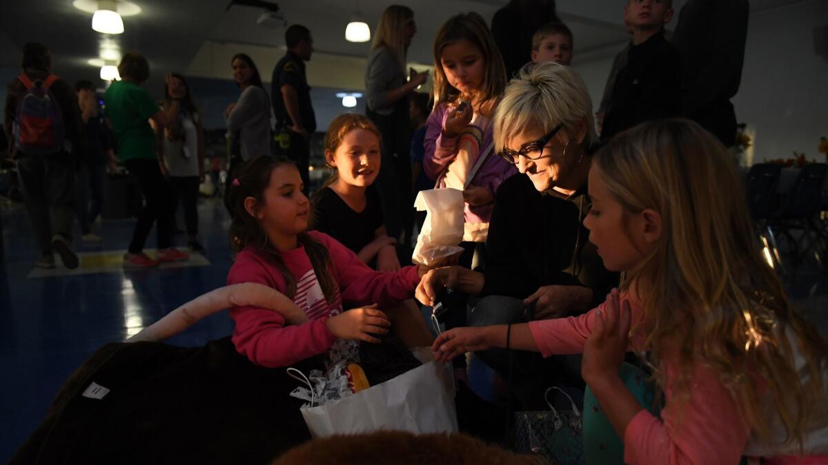 Robin Levy, right, whose home burned down in Malibu, is greeted with gifts from children of friends at a "Happy Friendsgiving" at Santa Monica High School on Tuesday.