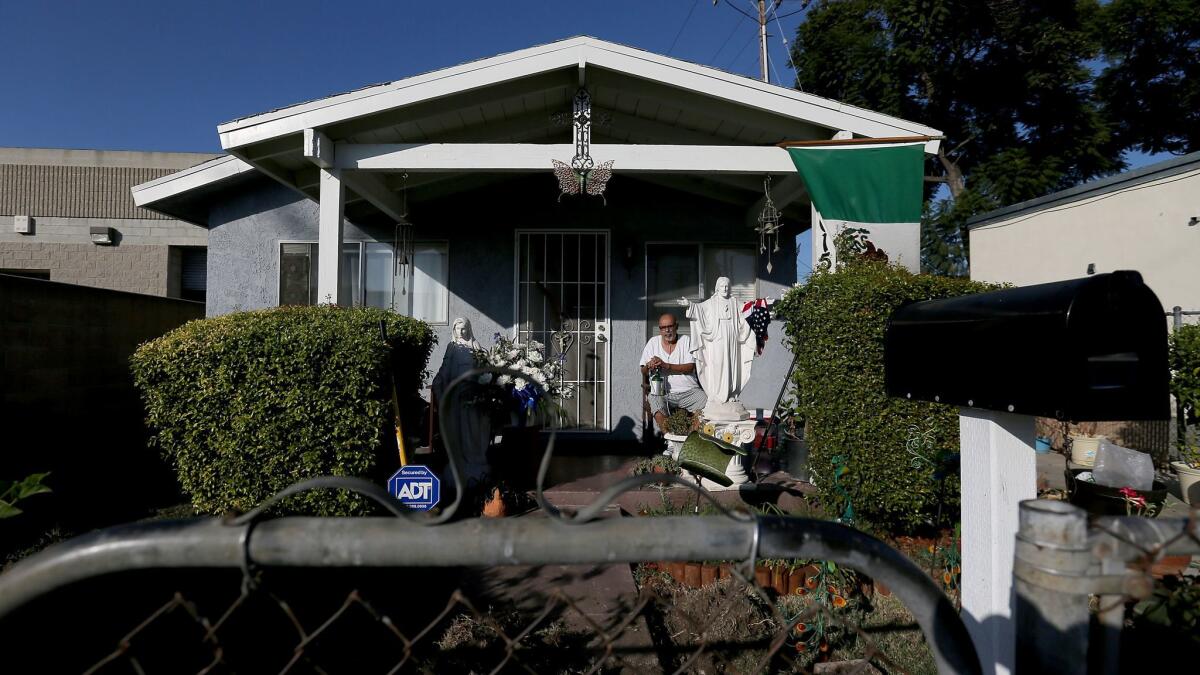 Michael Alva, 53, sits with his oxygen tank outside his home in a neighborhood in Paramount.