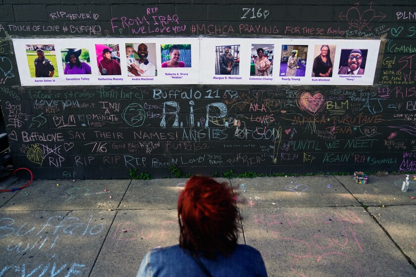 A person visits a memorial with pictures and writing on it.