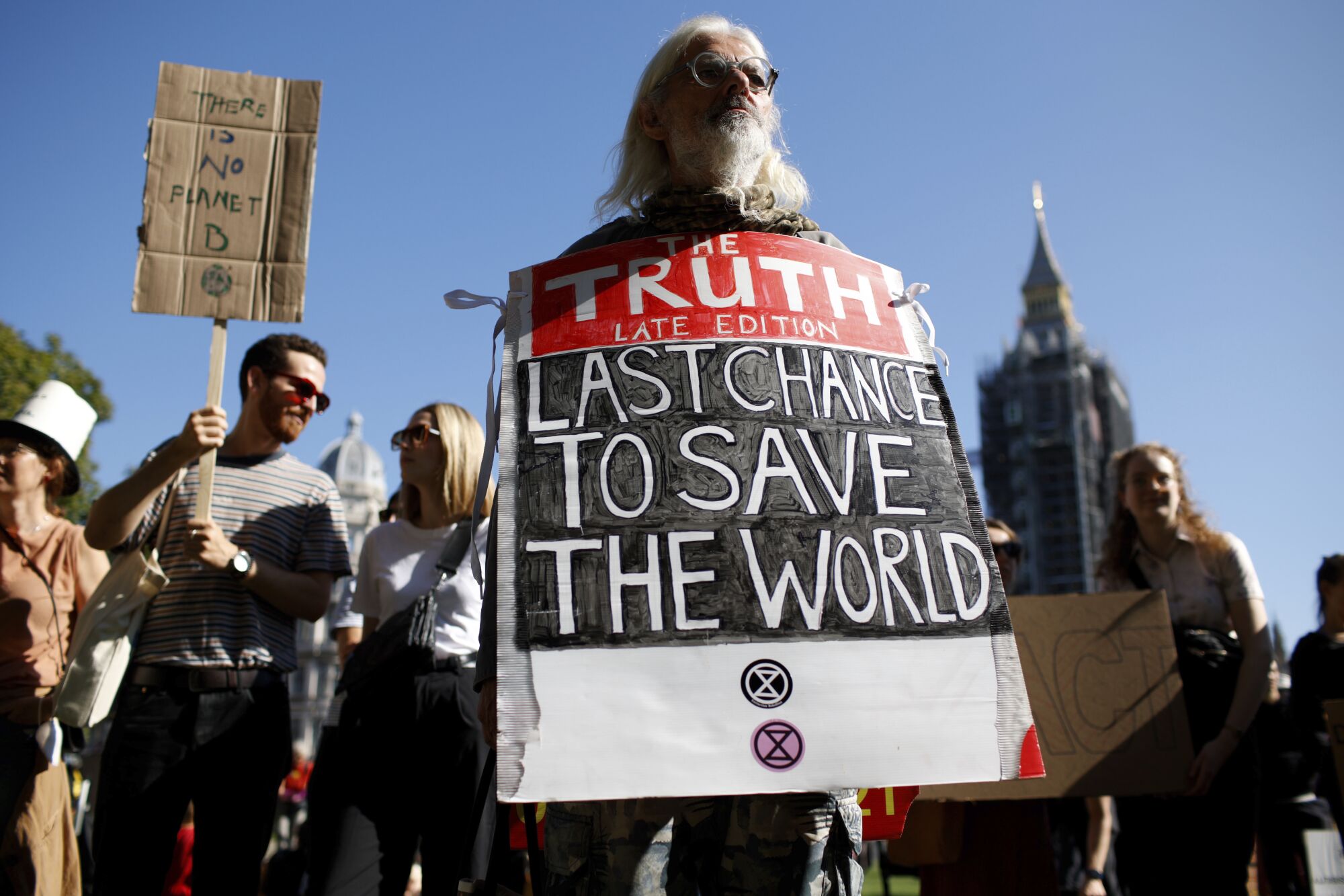 A man holds a sign that reads, "Last chance to save the world." 