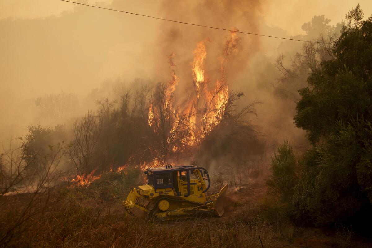 A bulldozer works near flames
