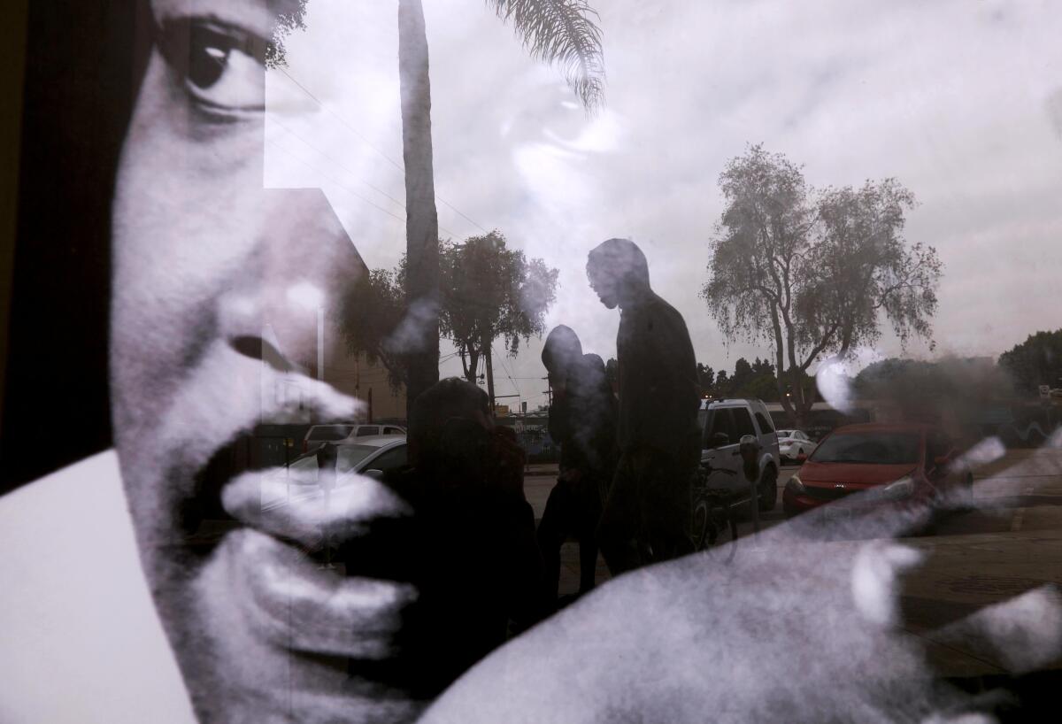 Pedestrians are seen in a reflection of Martin Luther King Jr. in Leimert Park.