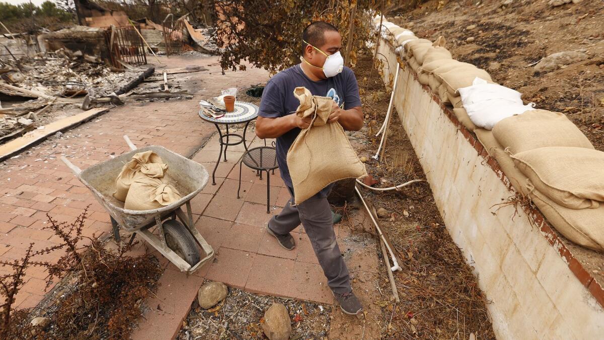 Jonathan Lopez places sandbags earlier this week to protect against erosion from a hillside and protect what's left of his home in Malibu. The first post-fire rainfall came and went without significant mudslides or debris flow from fire-scarred hillsides.
