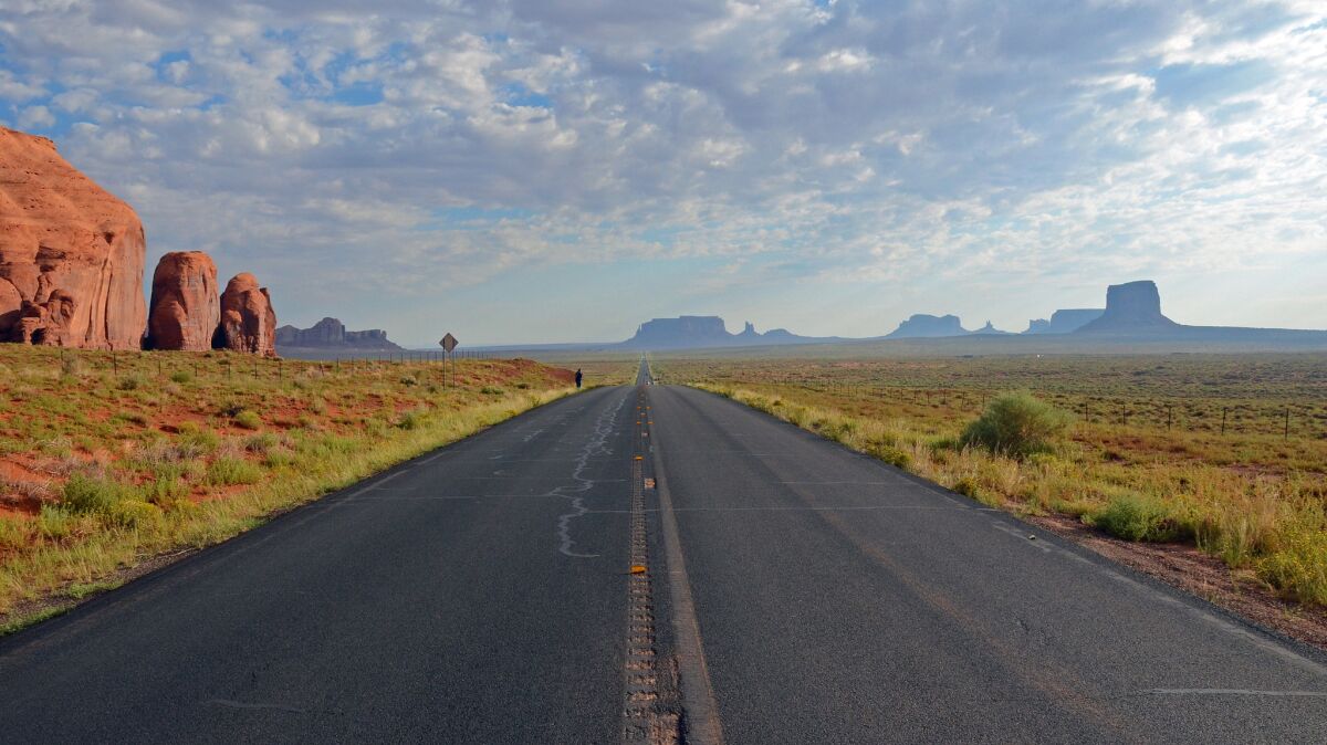A highway runs toward Monument Valley in Arizona.