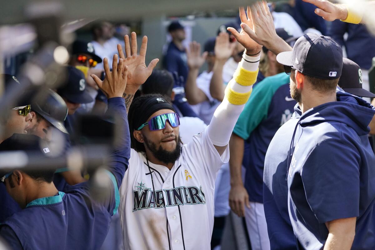 Seattle Mariners' J.P. Crawford is congratulated by teammates after scoring against the Houston Astros during the sixth inning of a baseball game Wednesday, Sept. 1, 2021, in Seattle. (AP Photo/Elaine Thompson)