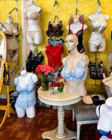 Half a mannequin in a light blue bra sits on a table surrounded by lingerie. 
