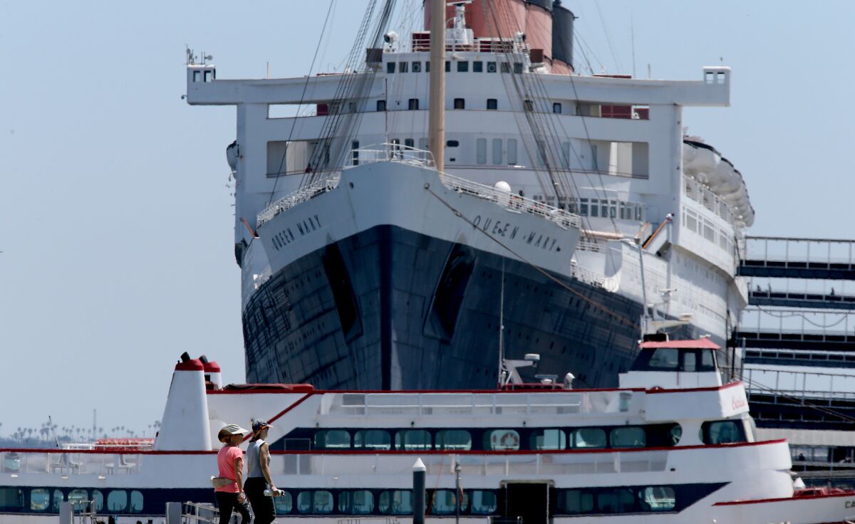 Strollers walk past the Queen Mary, a historic ocean liner that is permanently berthed in Long Beach.