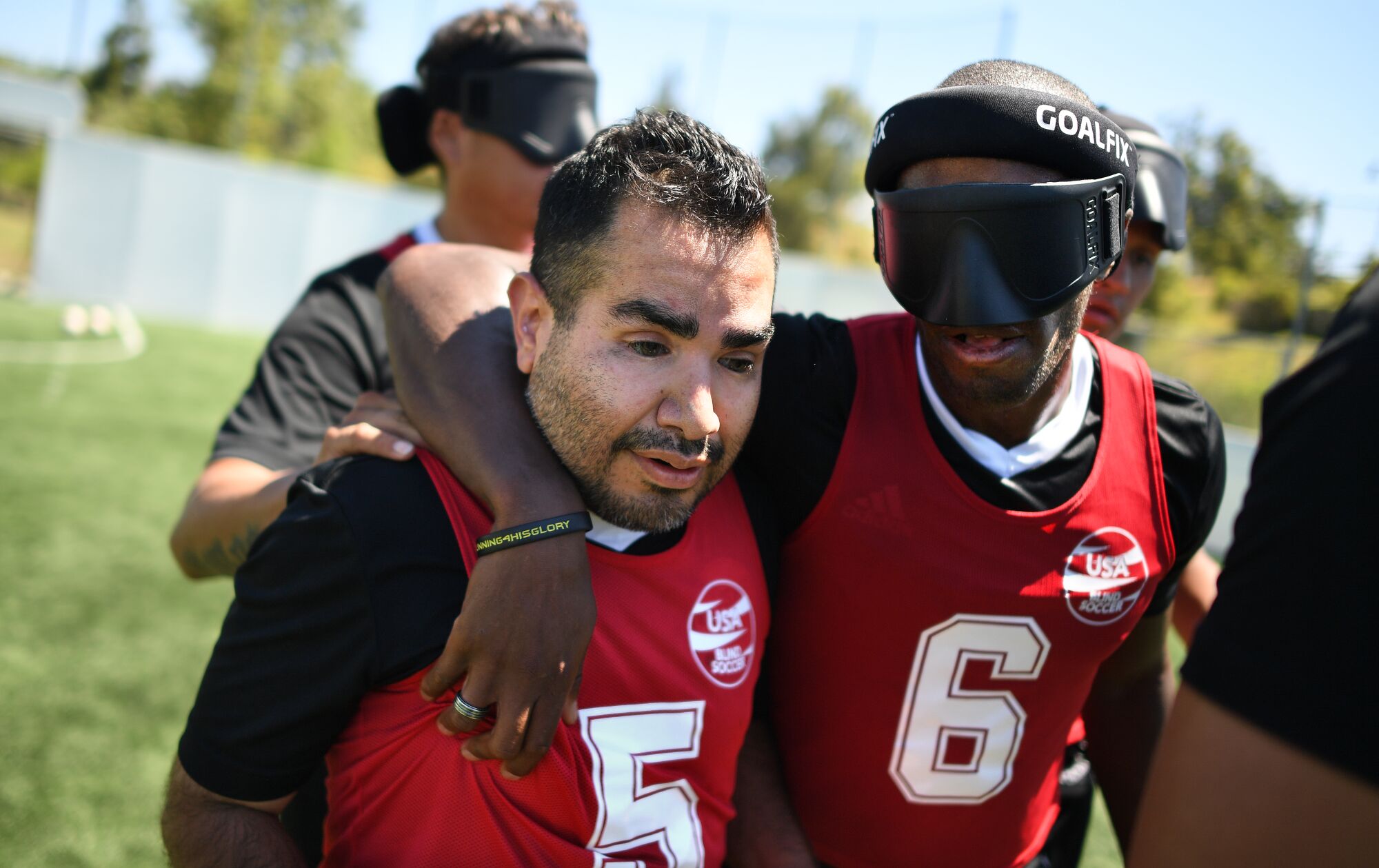 Blind soccer players Alvarado Mora Arellano and David Brown embrace following a scrimmage