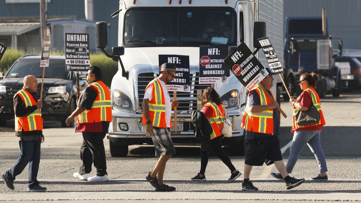 Port of Los Angeles and Port of Long Beach truck drivers and warehouse workers on Monday hold up picket signs in Wilmington.