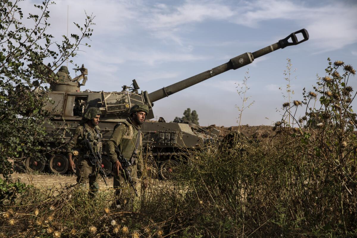 Dos soldados israelíes caminan junto a un tanque