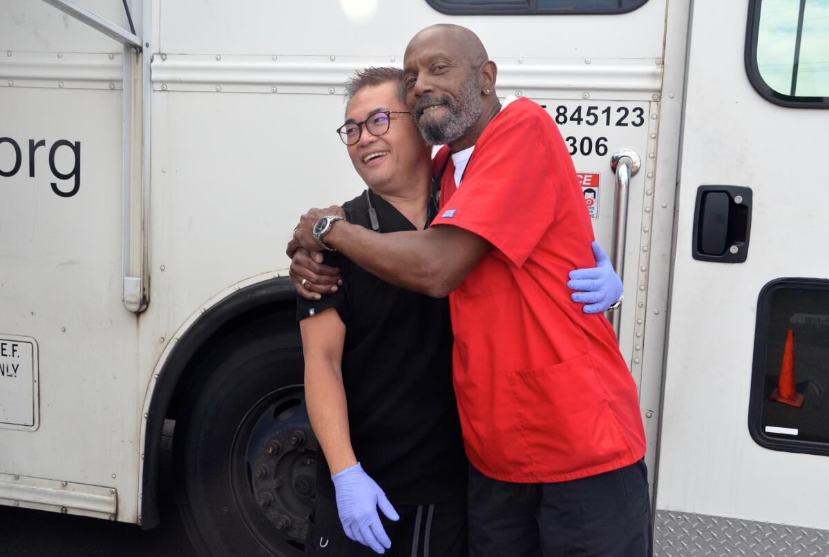 Mobile operator Bernard Deshone hugs  co-worker and registered nurse Richard Suhartono.