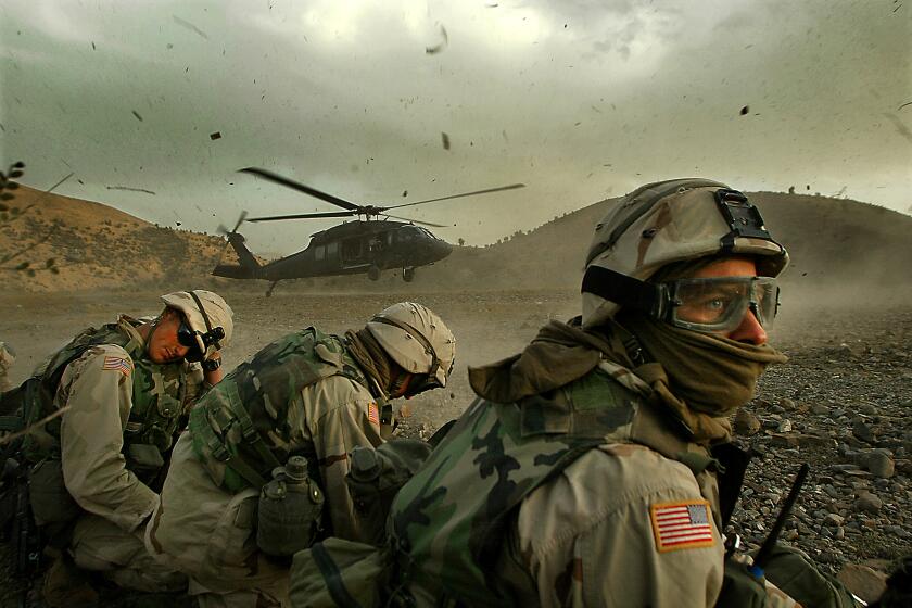 Members of the 82nd Airborne duck away from the debris being thrown into the air as a Blackhawk helicopter prepares to exfil soldiers on a mission searching remote villages in southeastern Afghanistan.