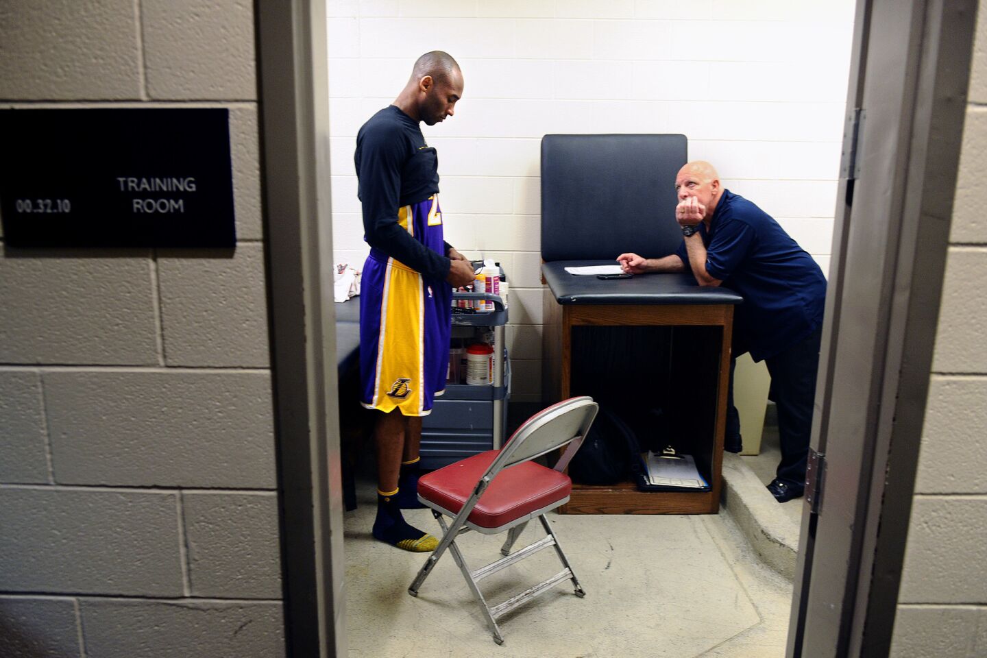 Kobe Bryant prepares for a game with the Rockets in the locker room as trainer Gary Vitti looks on in Houston.