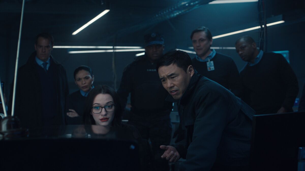 Kat Dennings, Randall Park and others crowding around a TV set in "WandaVision."
