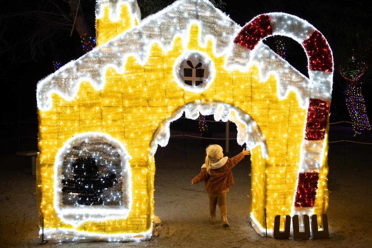 Illuminated cutout house with giant candy cane and tiny girl walking through