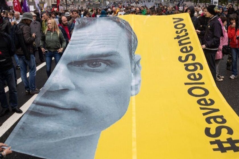 Protesters hold a poster with the image of political prisoner Oleg Sentsov during an opposition rally organised by 'Free Russia' in Moscow, Russia, Sunday, June 10, 2018. (AP Photo/Evgeny Feldman)