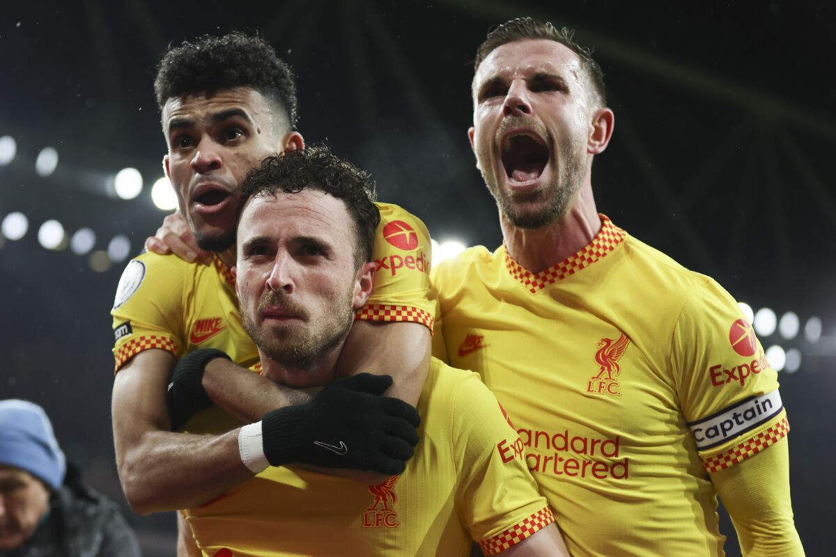 Liverpool's Diogo Jota, bottom, is congratulated by teammates Luis Diaz, top, and Jordan Henderson after scoring his team's first goal during the English Premier League soccer match between Arsenal and Liverpool at Emirates Stadium in London, Wednesday, March 16, 2022. (AP Photo/Ian Walton)
