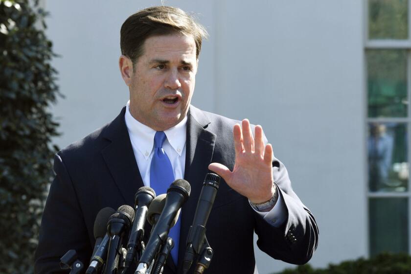 FILE - In this April 3, 2019, file photo, Arizona Gov. Doug Ducey talks to reporters outside the West Wing of the White House in Washington. Ducey is yanking a grant of up to $1 million from Nike amid a report that the athletic company pulled a flag-themed shoe from the market. (AP Photo/Susan Walsh, File)