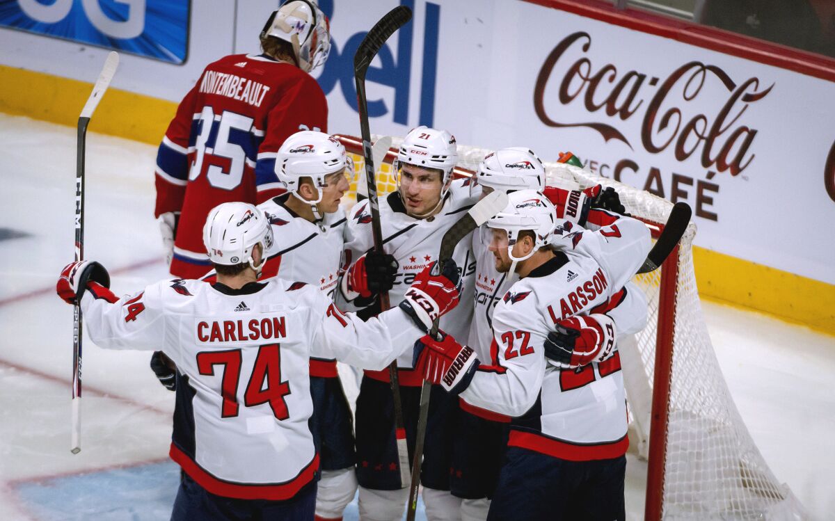 Washington Capitals right wing Garnet Hathaway, center, celebrates his goal against Montreal Canadiens goaltender Sam Montembeault (35) with teammates during the third period of an NHL hockey game Saturday, April 16, 2022, in Montreal. (Peter McCabe/The Canadian Press via AP)
