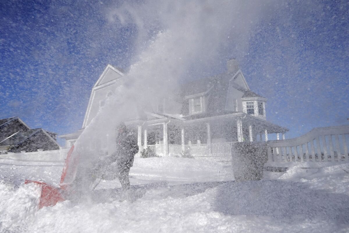 Bill McKelvey uses a snow blower to clear snow in front of his home, Sunday, Jan. 30, 2022, in Scituate, Mass. (AP Photo/Steven Senne)
