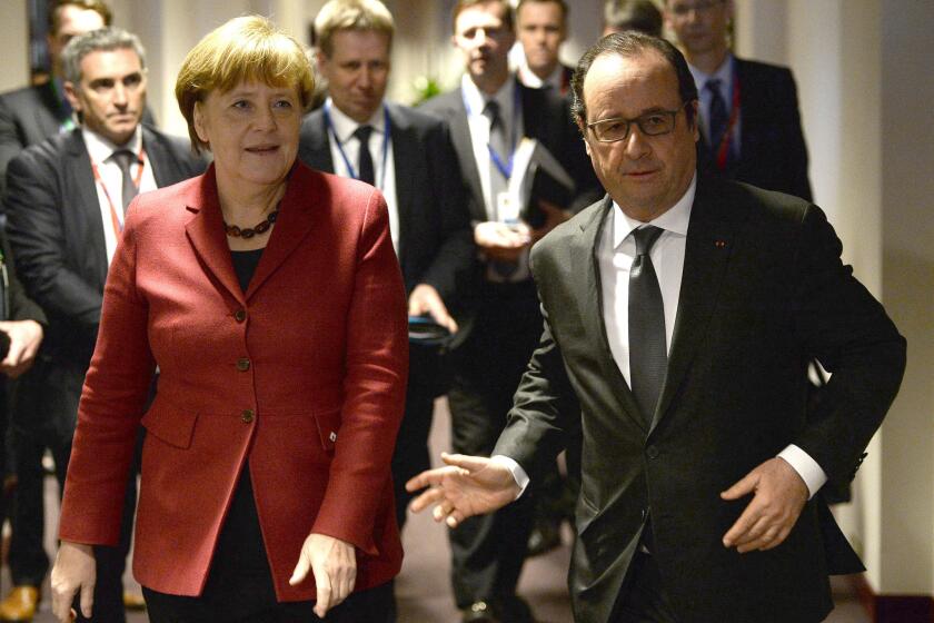 French President Francois Hollande walks with German Chancellor Angela Merkel before a meeting on the sidelines of a European Union summit in Brussels on Thursday.