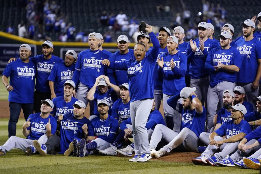 Los Angeles Dodgers manager Dave Roberts, front, cheers with the team in the background after the Dodgers' baseball game against the Arizona Diamondbacks in Phoenix, Tuesday, Sept. 13, 2022. The Dodgers won 4-0 and clinched the National League West. (AP Photo/Ross D. Franklin)