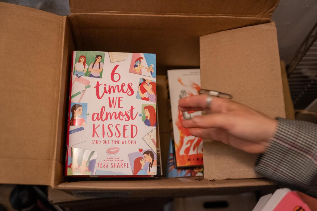 A hand rests on a box of books.