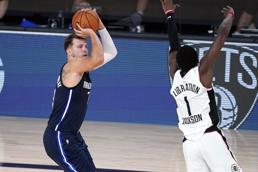 Dallas Mavericks' Luka Doncic (77) shoots his game-winning 3-point basket as Los Angeles Clippers' Reggie Jackson.