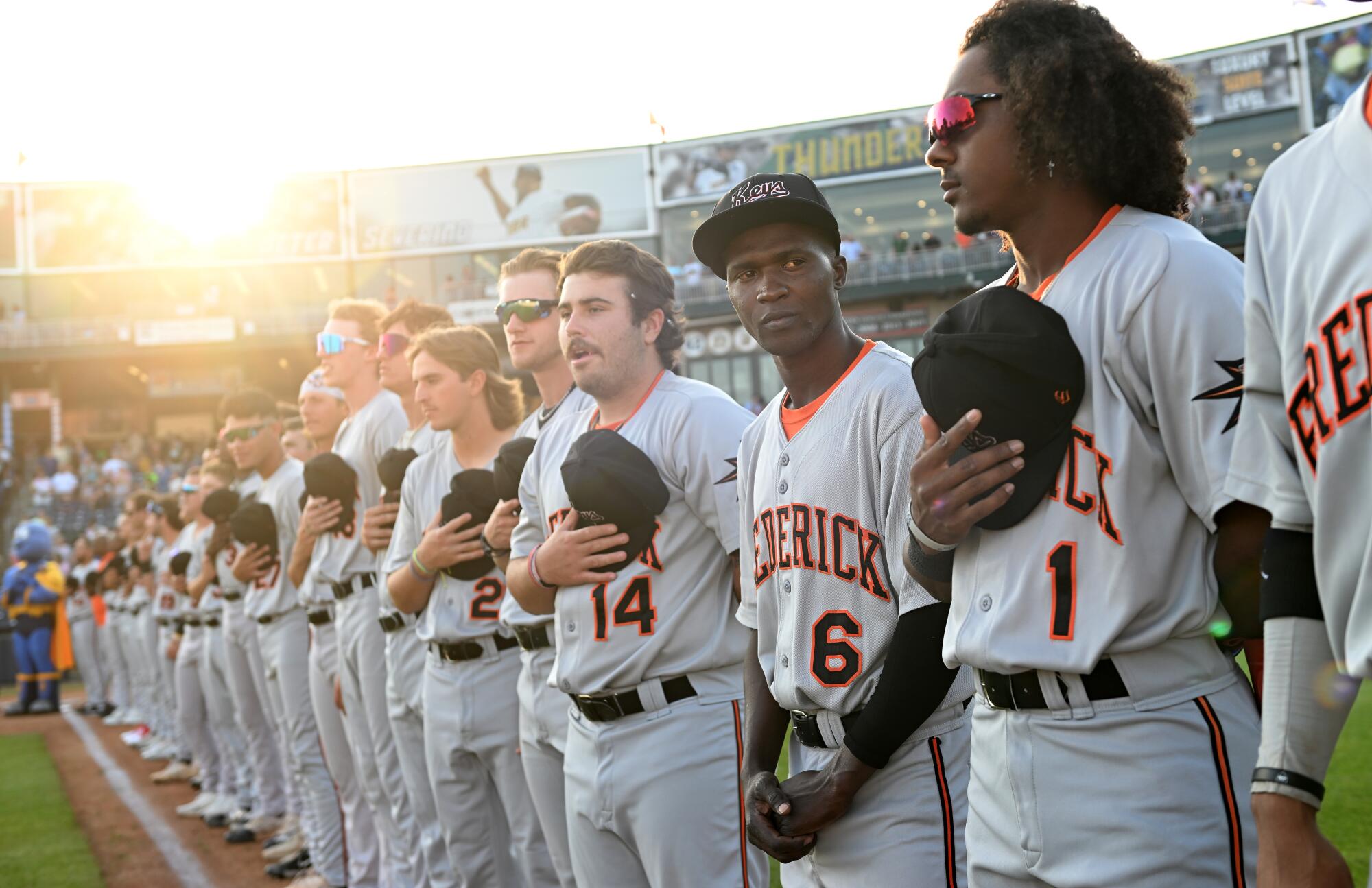 Not understanding the etiquette of the national anthem, Frederick Keys player Dennis Kasumba looks to teammates for guidance.