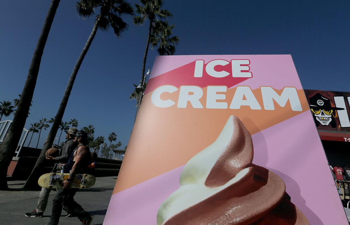Beachgoers walk past a sign advertising ice cream on the Venice boardwalk Wednesday.