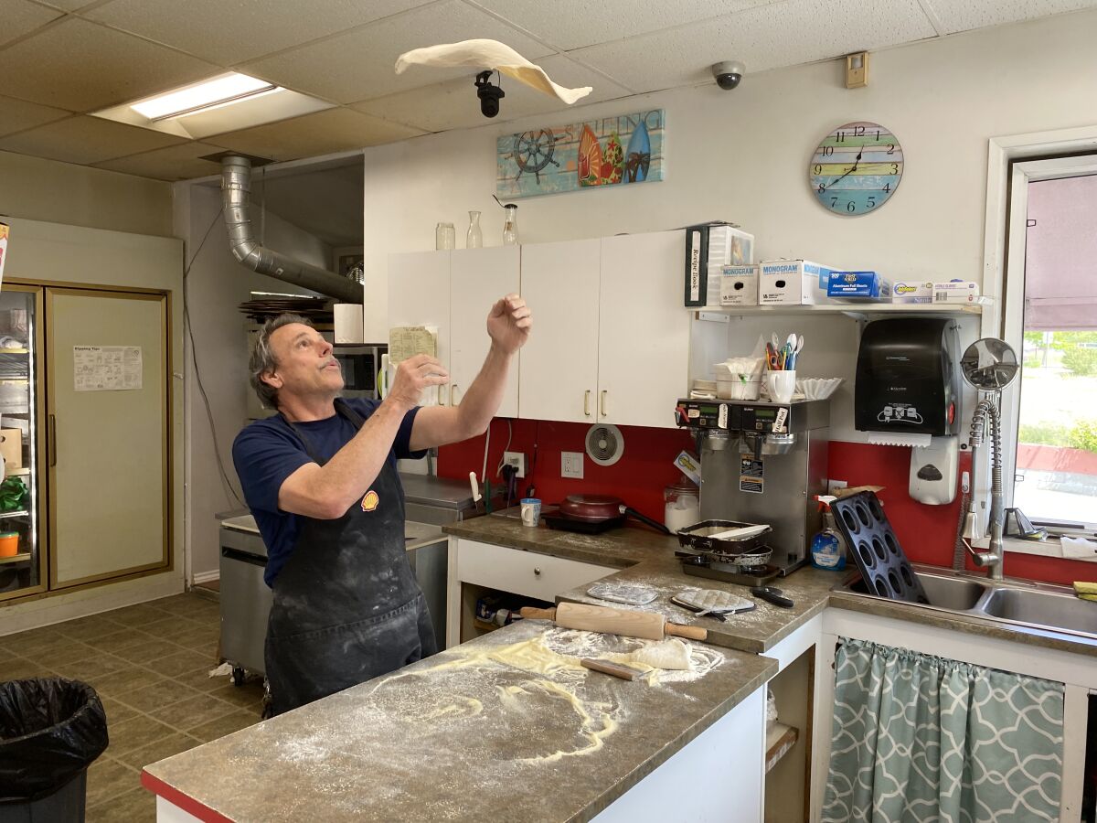 A man tosses pizza dough