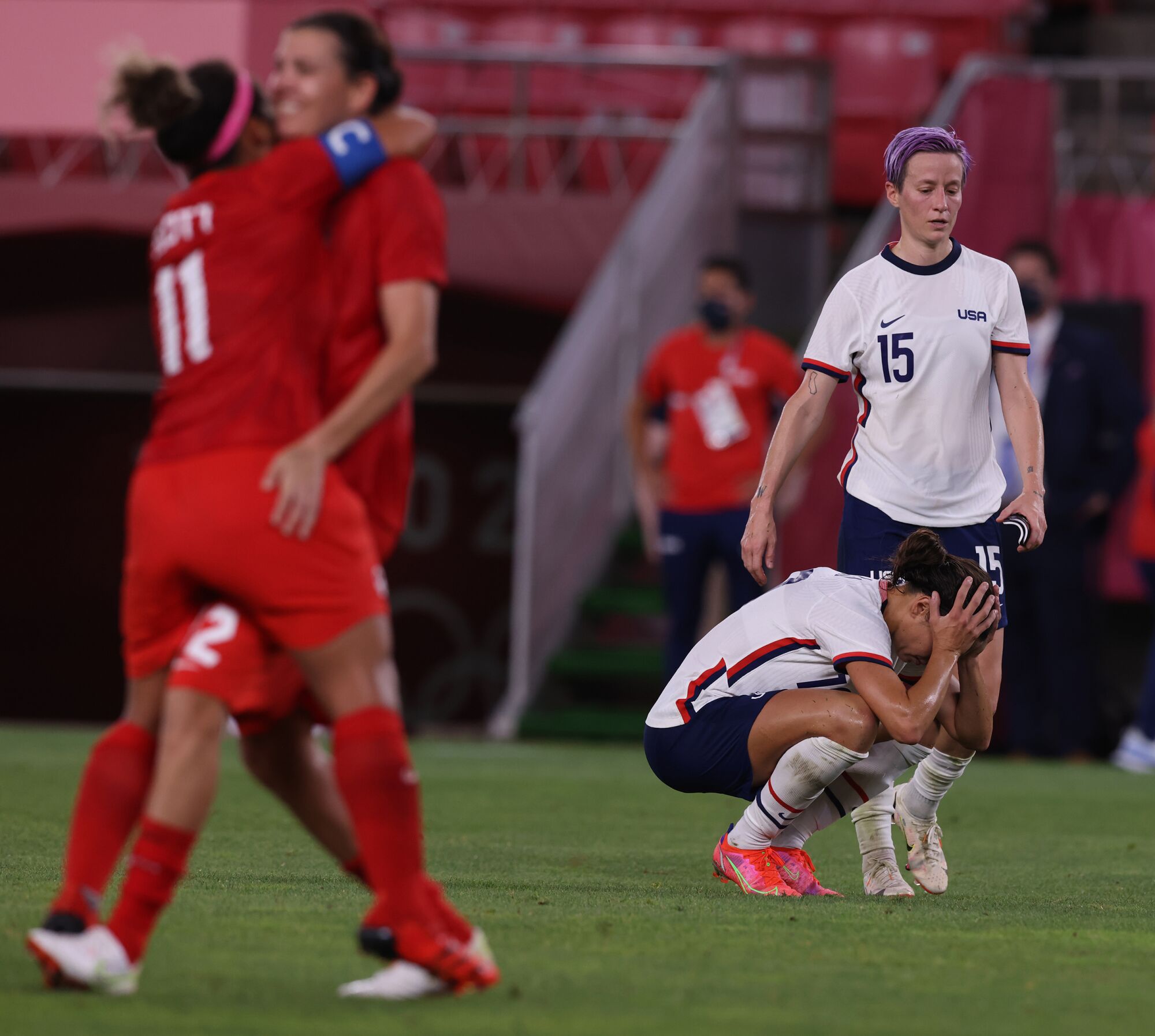 A despondent Team USA forward Carli Lloyd (10) crouches on the field as teammate Megan Rapinoe approaches to console her.