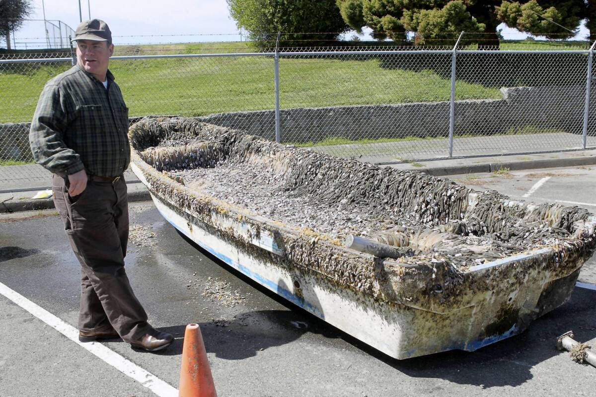 Troy Nicolini of the National Oceanic and Atmospheric Administration's National Weather Service inspects the Japanese boat that washed up in Crescent City.