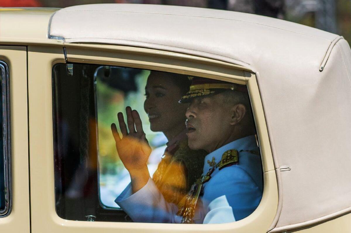 Thailand's King Maha Vajiralongkorn waves as he arrives with Queen Suthida for his coronation.