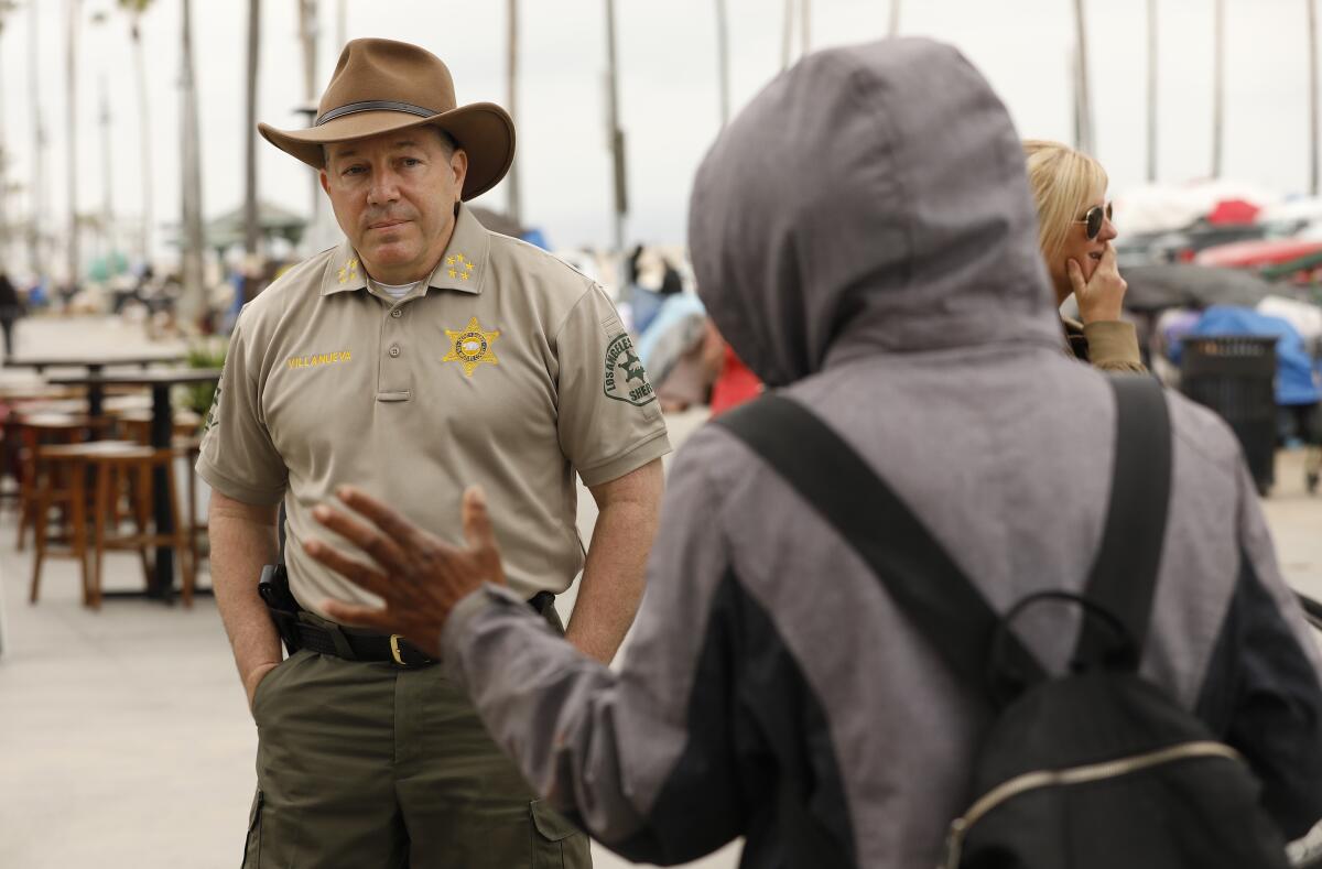 Alex Villanueva listens as a person speaks to him on the Venice boardwalk