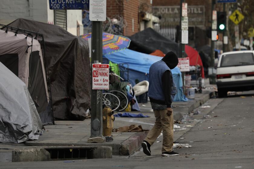 LOS ANGELES, CALIFORNIAÑNOV. 19, 2019ÑA man walks down 6th Street on the road, since the sidewalk is blocked by tents. LAPD has in the past issued tickets to homeless people who pitch a tent on the sidewalks blocking the way for pedestrians. However, people can receive legal assistance at LACAN, which stands form Los Angeles Community Action Network. Photographs taken on Nov. 19, 2019. (Carolyn Cole/Los Angeles Times)