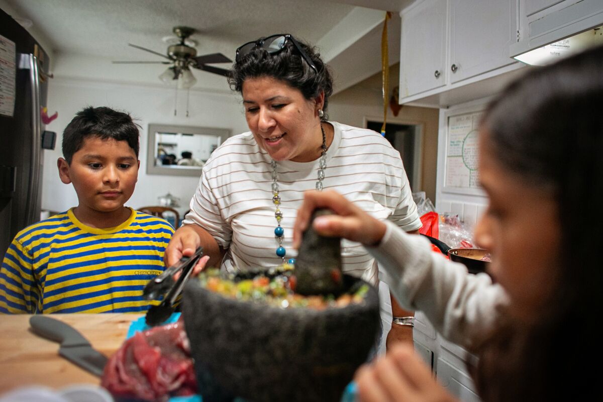 Luz Puebla cooks dinner with her son Eros Llanez,10, and daughter Evolet Llanez, 8, in South Gate.