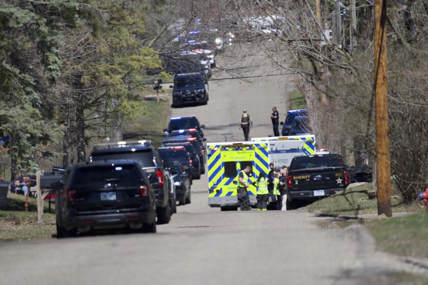 Law enforcement line the street near Mayview Road and North St. in Minnetonka, Minn., Wednesday, April 10, 2024. Two Hennepin County sheriff's deputies were injured while serving a warrant and a suspect was killed during an exchange of gunfire in the Minneapolis suburb of Minnetonka on Wednesday, authorities said. (Shari L. Gross/Star Tribune via AP)