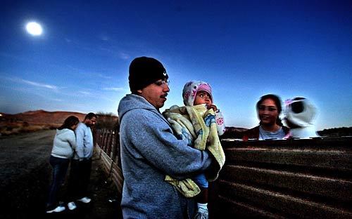 Beneath a full moon, siblings holding babies chat at the border fence - a family bisected by a line in the desert. Generations once crossed at will, but the barrier changed that.
