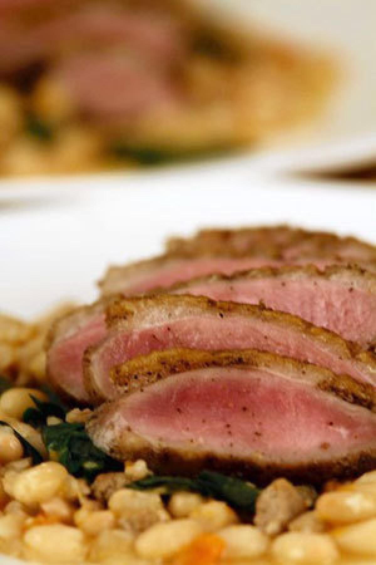 Crisp-skinned duck breast on white beans with dandelion greens.