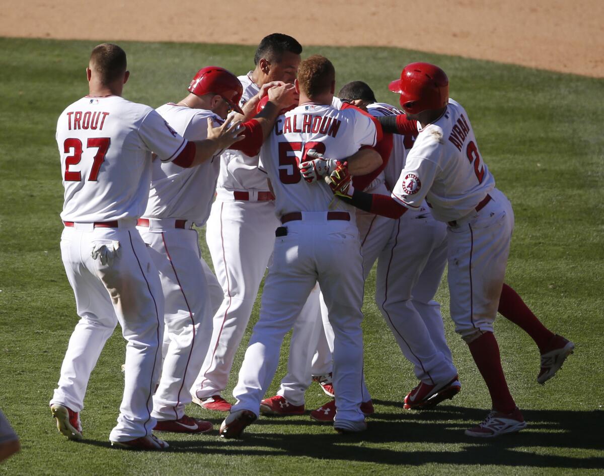 Angels third baseman Taylor Featherston is mobbed by his teammates after hitting a walk-off single in the 13th inning against the Houston Astros. The Angels beat the Astros, 2-1.