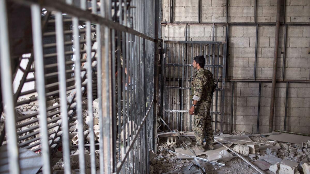 Members of the U.S.-backed Syrian Democratic Forces walk inside a prison built by Islamic State at a stadium in Raqqah, Syria, in October. An Amerian citizen accused of fighting for the militant group is being detained in Iraq by the U.S.