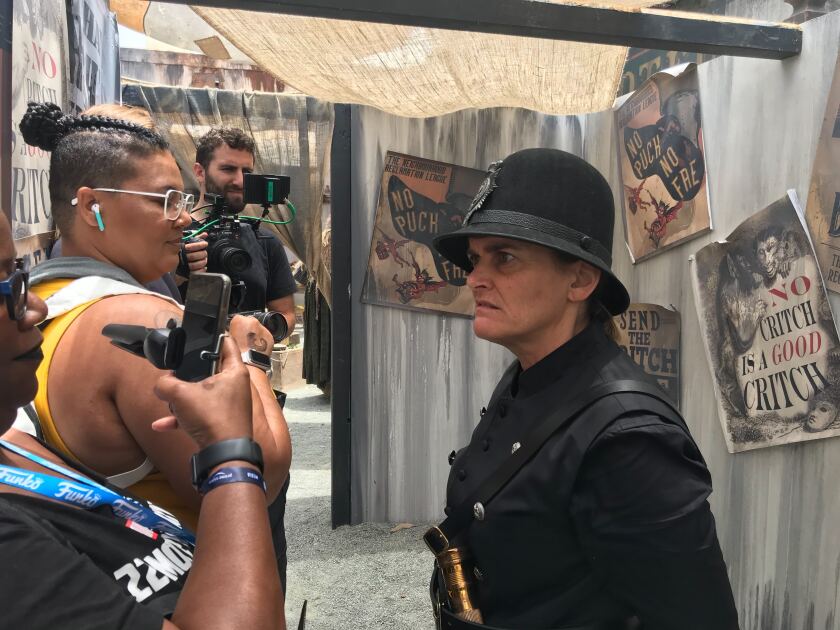 An actress portraying a policewoman yells at attendees in line for the Amazon Prime Video installation for the TV show "Carnival Row" in downtown San Diego.