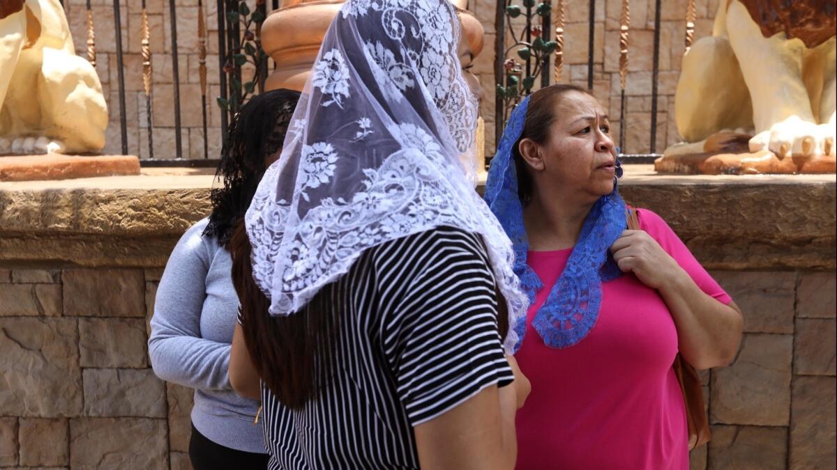 Congregants stand in front of La Luz Del Mundo as other members pray inside the church in East Los Angeles.