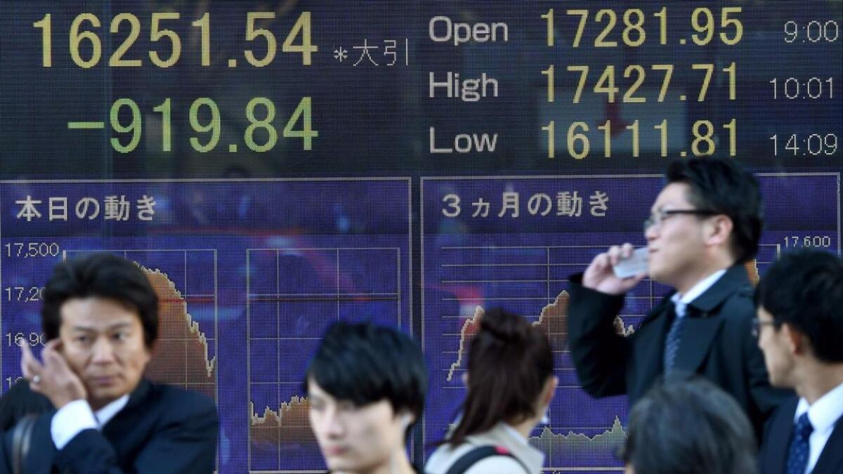 People in Tokyo walk past an electric quotation board flashing the Nikkei key index of the Tokyo Stock Exchange. Japanese shares went into free fall at news of Donald Trump's win.